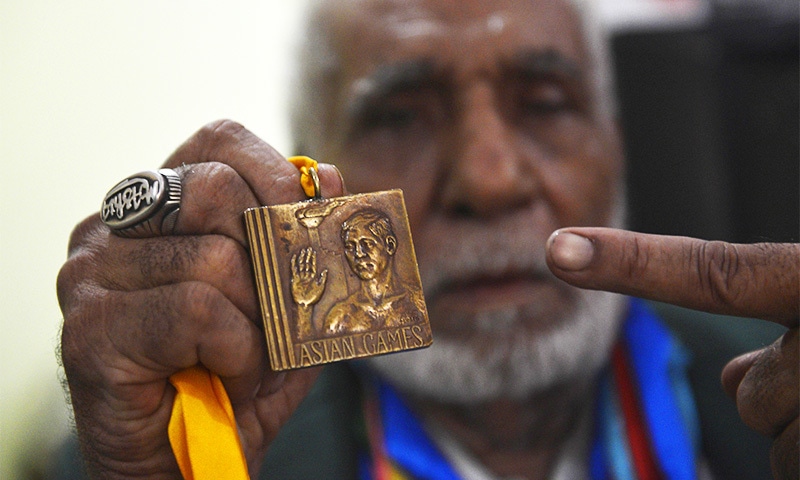 In this photo taken on June 23, 2016, former Pakistani Olympian Muhammad Ashiq holds his medals as he posses at his residence in Lahore. Ashiq, who competed for Pakistan at the 1960 and the 1964 Olympics, now scrapes by as a rickshaw driver in the teeming eastern city of Lahore. / AFP PHOTO / ARIF ALI
